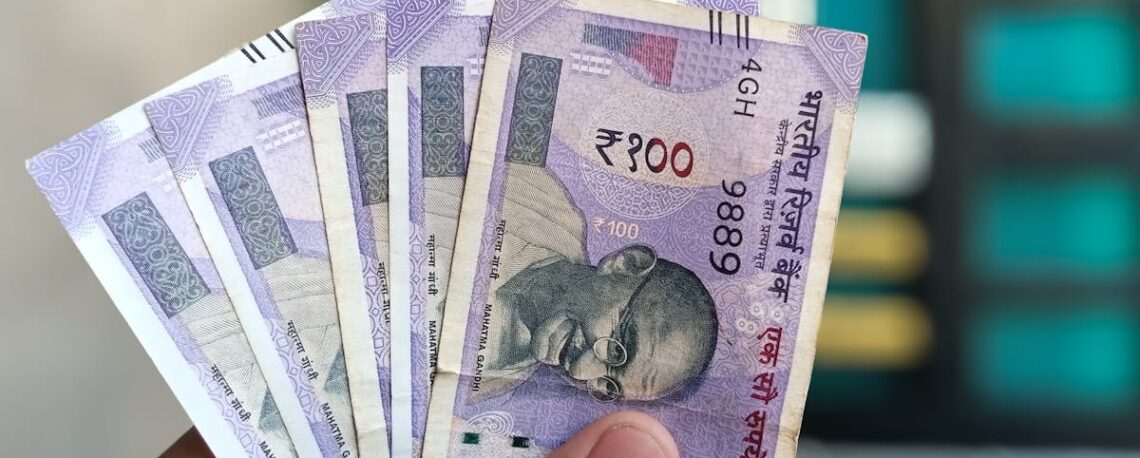 Close-up view of holding Indian 100 rupee banknotes, showcasing currency details and design.